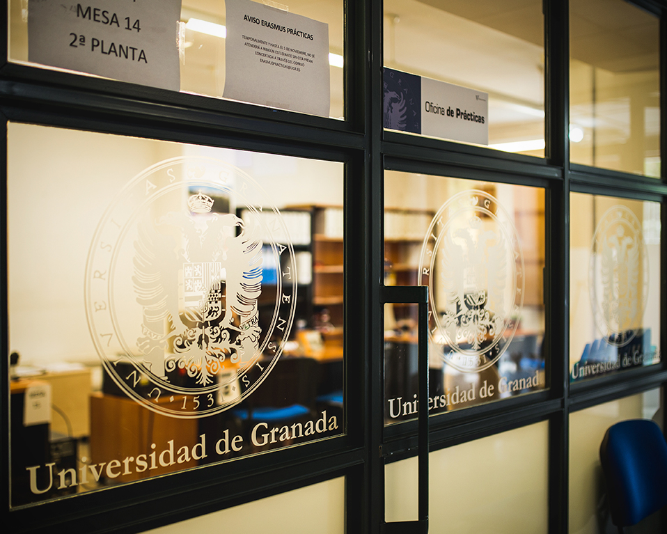 Vista de los cristales serigrafiados con el logotipo de la Universidad de Granada en la Oficina de Prácticas del Centro de Promoción de Empleo y Prácticas